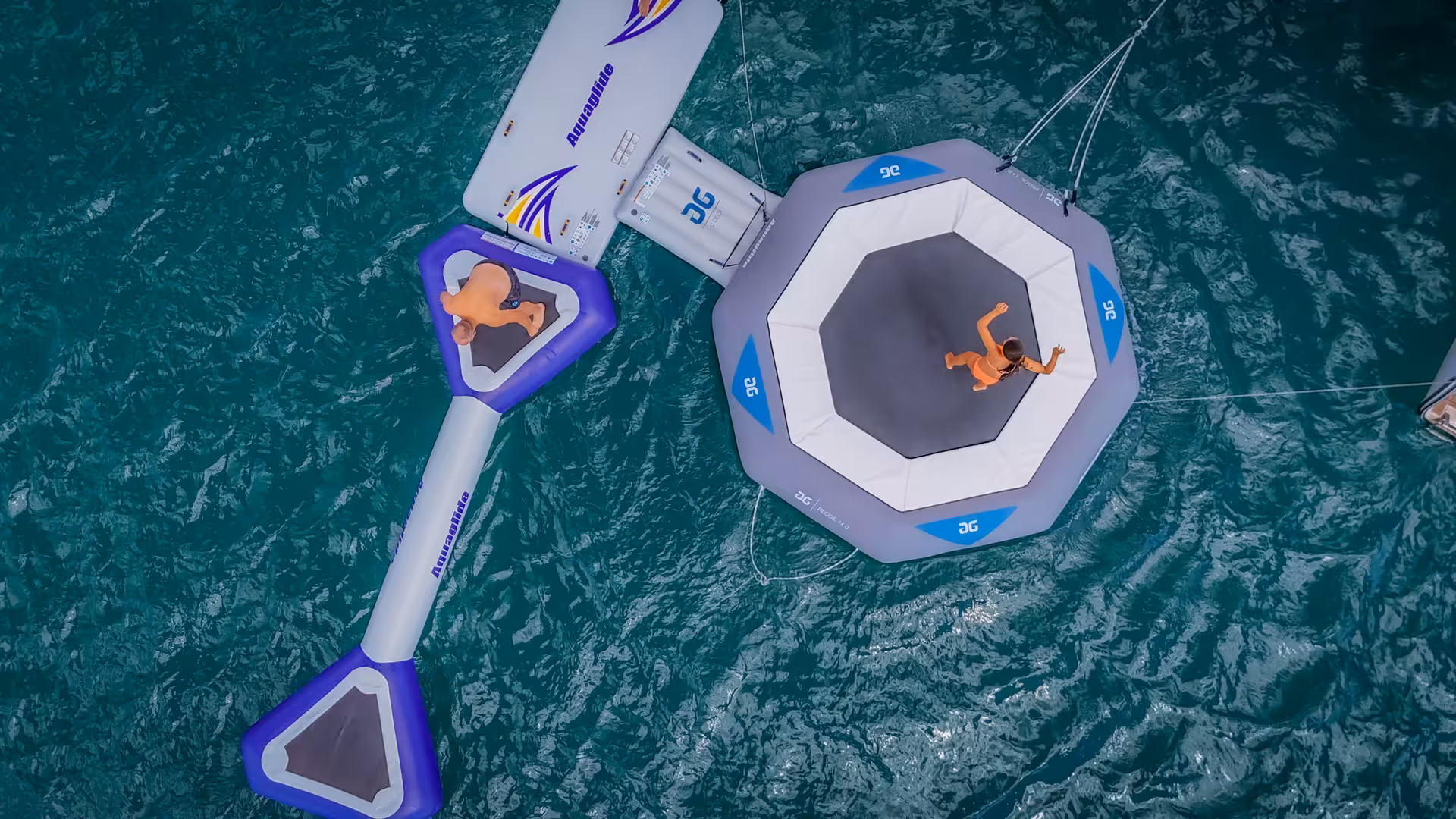 Aerial view of floating water trampoline and slide during a fun catamaran tour in Lagos Algarve