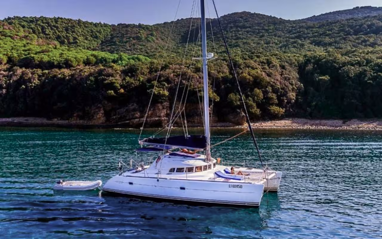 Experience tranquility aboard a sleek catamaran surrounded by the lush greenery of La Maddalena Archipelago near Cannigione.