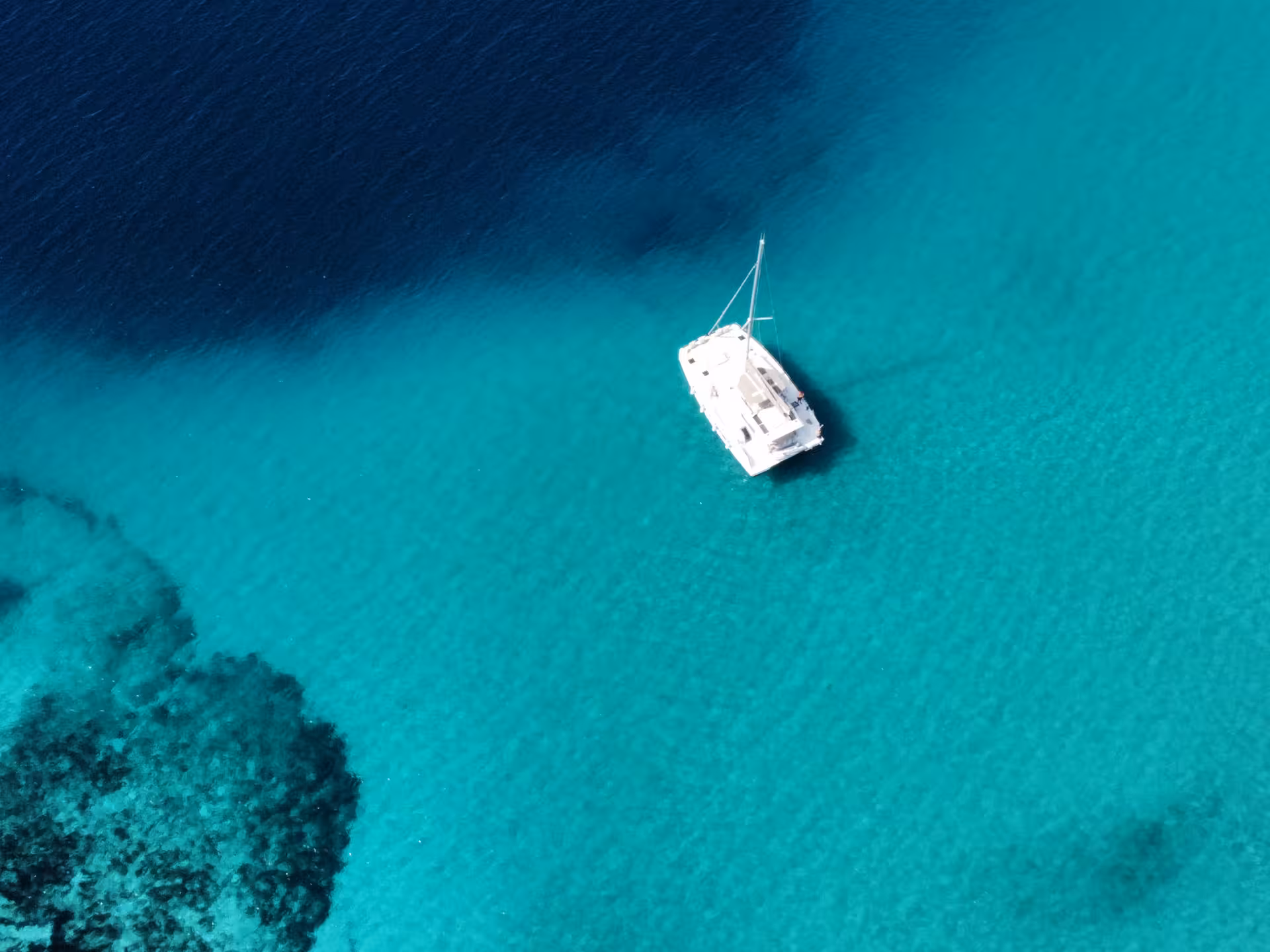 Aerial view of catamaran in turquoise lagoon, Archipelago Adventure sailing and snorkeling tour