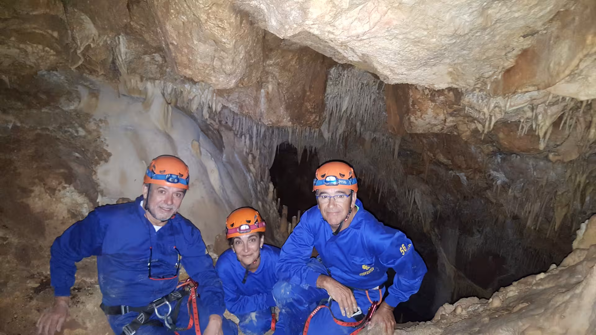 Participantes con mono y casco en cueva de Ejulve, Teruel, tour de espeleología de iniciación