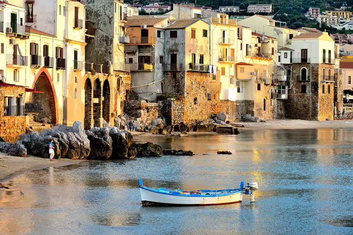 Colorful seafront houses and a traditional fishing boat in Cefalù bay, a highlight of the Monreale, Bagheria and Cefalù private tour