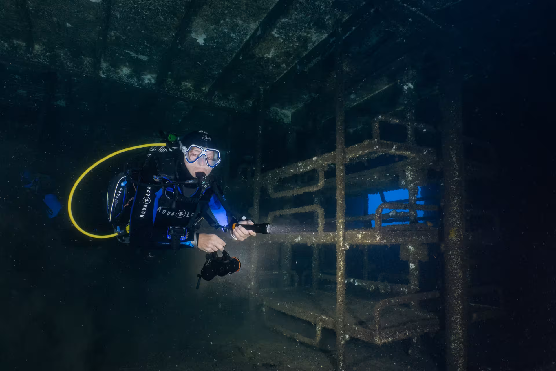 Diver explores the eerie interior of a sunken shipwreck, revealing history beneath the waves.