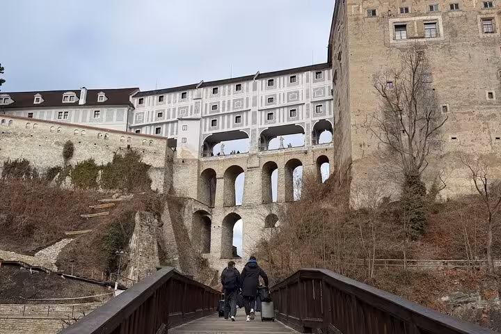 Visitors crossing bridge to Cesky Krumlov Castle arches on a private day tour from Vienna, Czech Republic