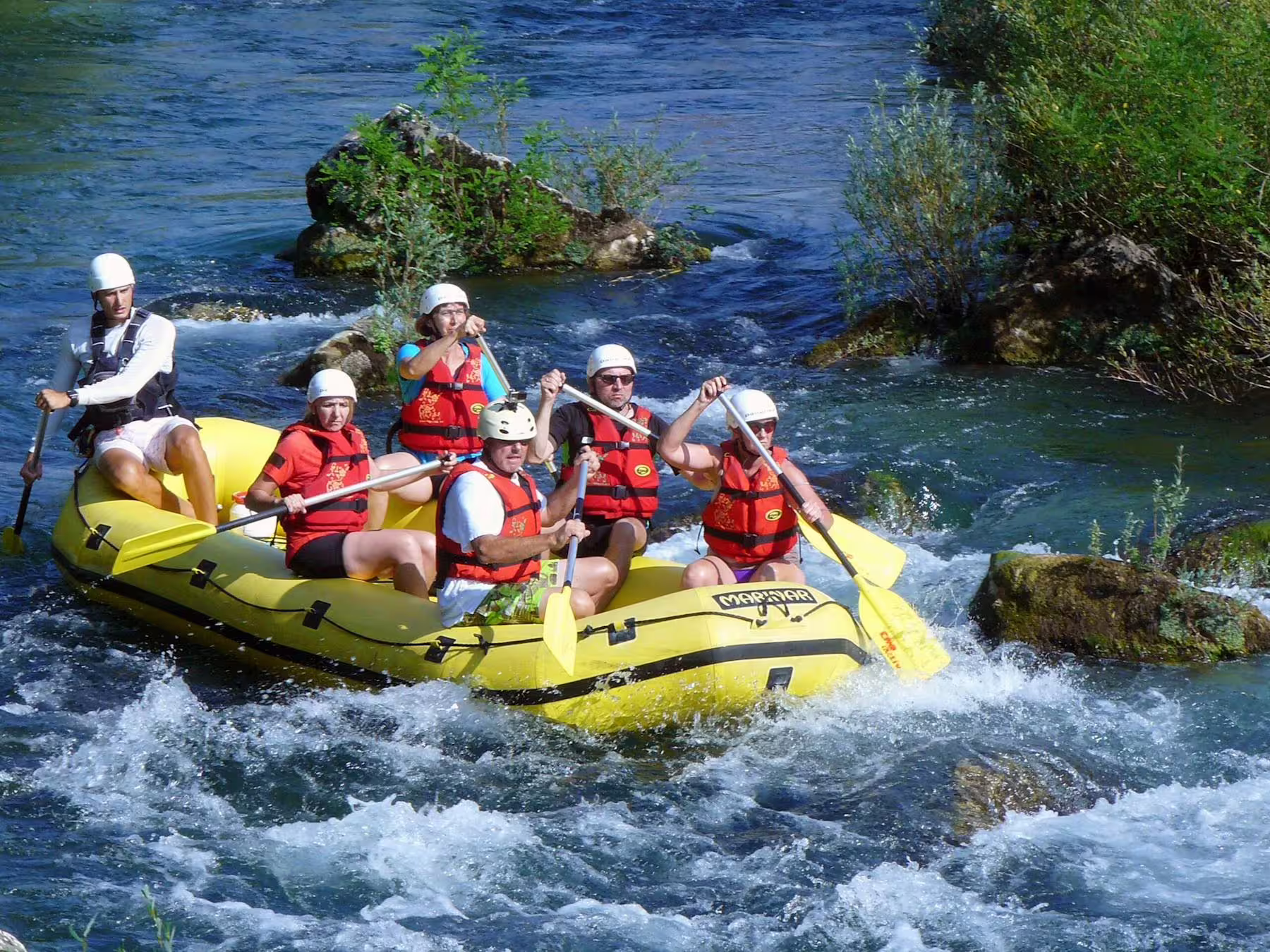 Guided Cetina River rafting near Makarska Riviera, group in yellow raft paddling through lively rapids