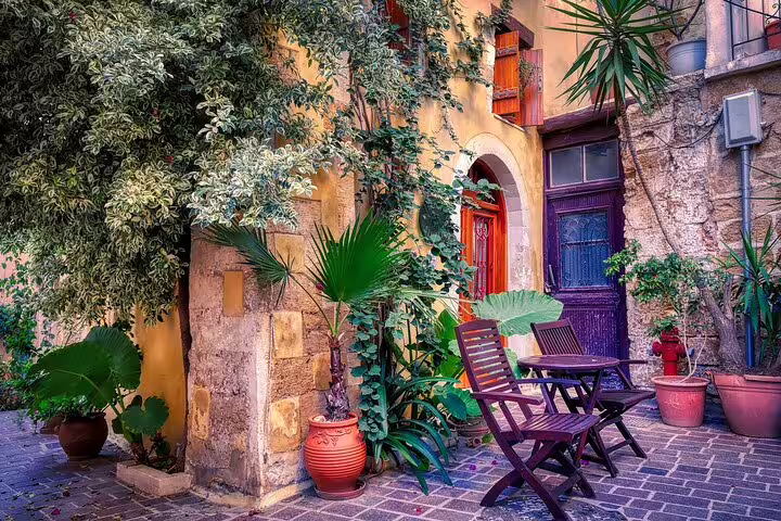 Charming courtyard in Chania, Crete, with lush greenery and rustic chairs, capturing the essence of a private West Crete tour.