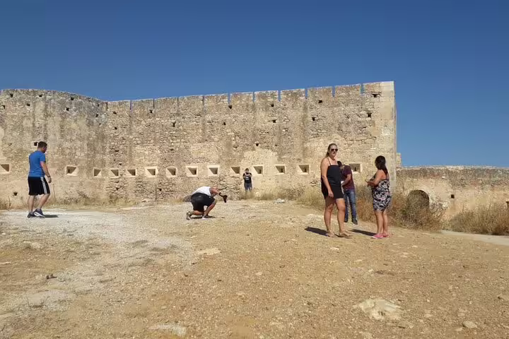 Visitors exploring the historic stone fortress in Chania, enjoying the sunny weather and rich cultural atmosphere.