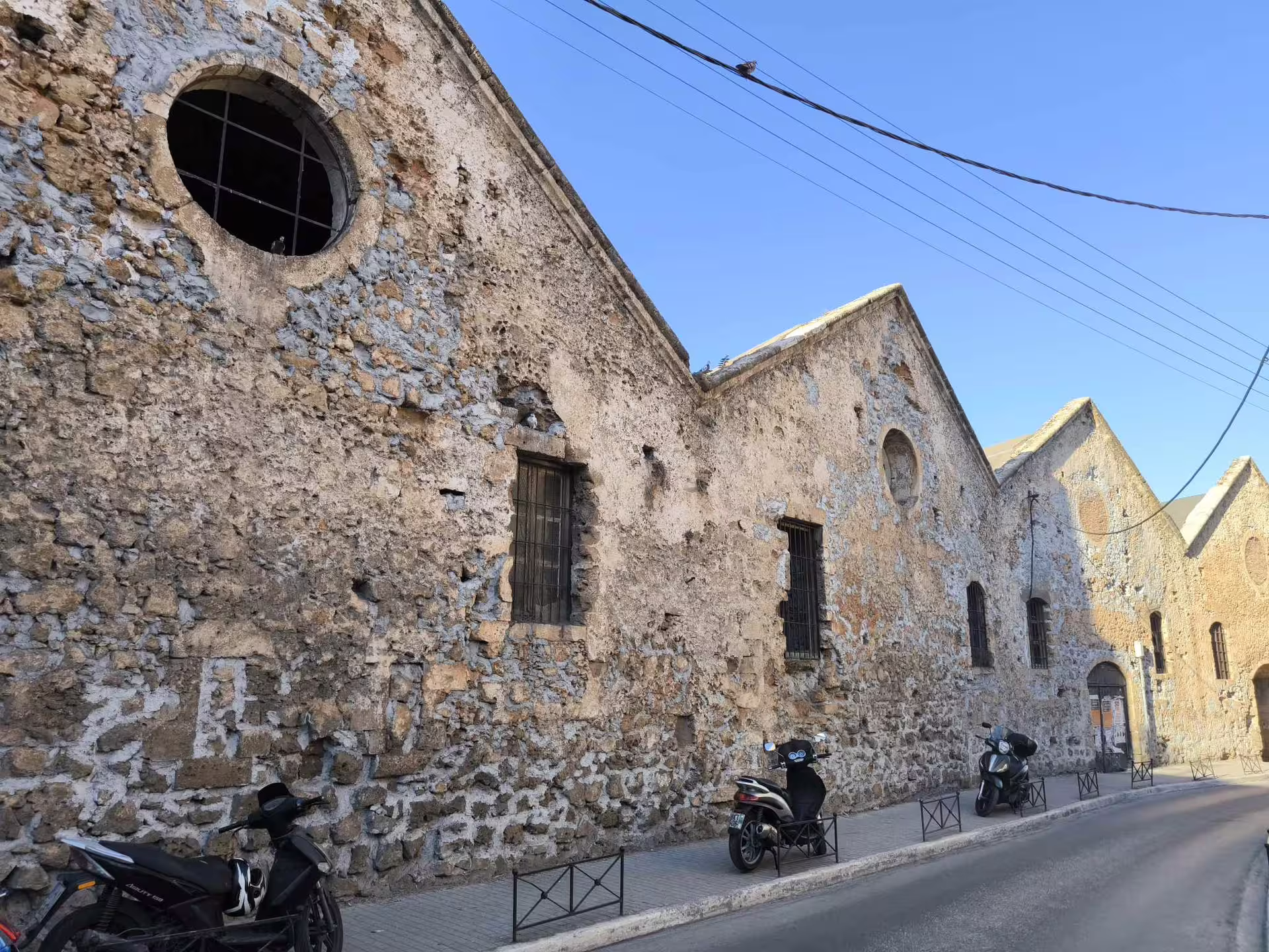 Historic stone buildings line a quiet street in Chania, showcasing the rich heritage of the Explore Aptera & Chania tour.