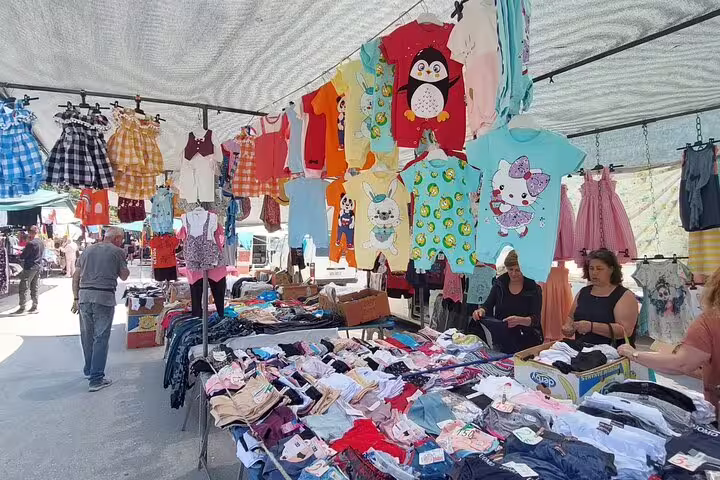 Colorful children's clothing stall at Chania's market, showcasing playful designs and a variety of garments.