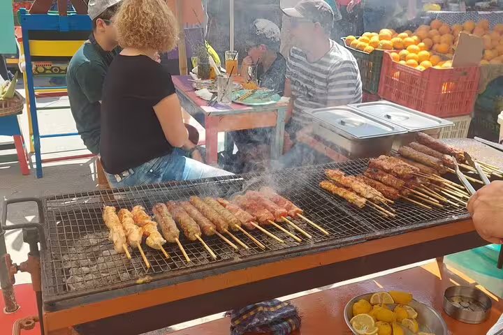 Sizzling skewers on a grill at Chania's market, surrounded by diners enjoying authentic Greek street food.