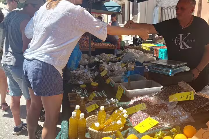 Tourists explore Chania's vibrant farmers market, purchasing local produce and goods from friendly vendors.