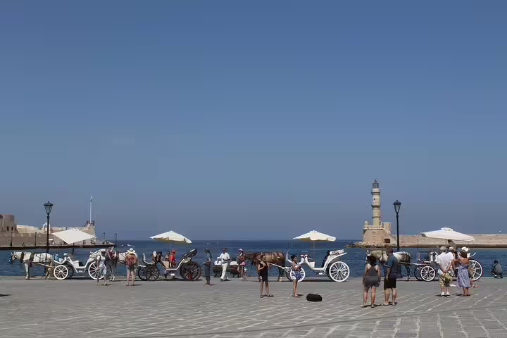Horse-drawn carriages and lighthouse at Chania's Old Town harbor, a picturesque stop on the tour.