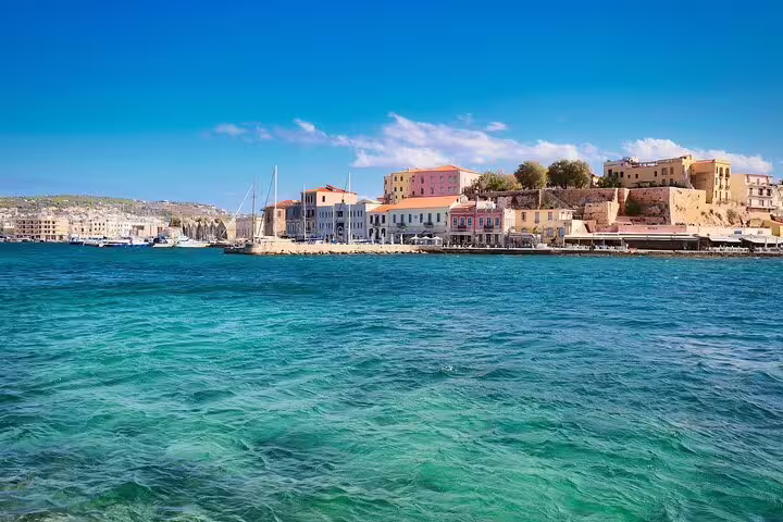 Scenic view of Chania Old Town waterfront with colorful buildings and clear blue sea under a bright sky.