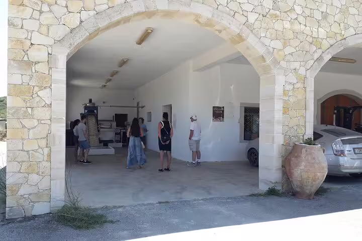 Visitors exploring the interior of an olive oil mill in Chania, featuring stone archways and traditional equipment.