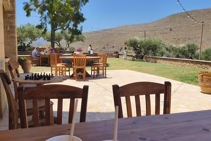 Relaxing outdoor seating area at Chania Old Town's olive oil mill, surrounded by olive trees and scenic hills.