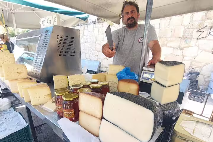 Discover Chania's Public Market with an array of local cheeses and honey, expertly showcased by a welcoming vendor.