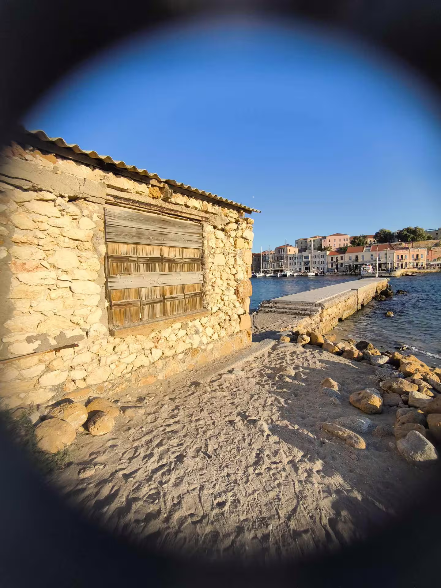 Charming rustic stone building by the serene waterfront in Chania at sunset during the Aptera tour.
