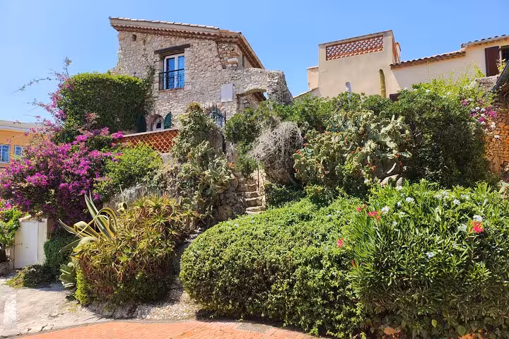 Charming stone house with vibrant flowers and lush greenery on the scenic French Riviera.