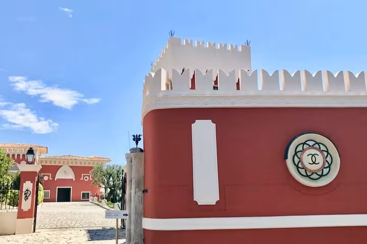 Charming red and white chateau entrance under blue skies on Nice City and Villefranche sur Mer private tour.