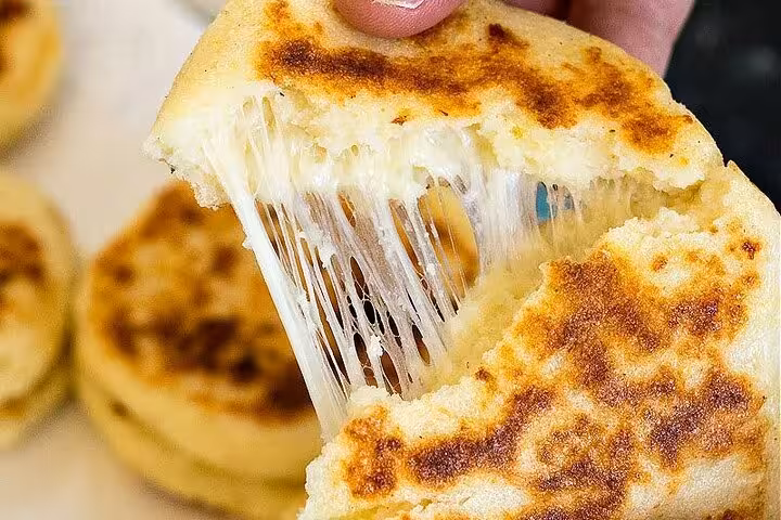 Cheese-filled arepas being pulled apart, highlighting a delicious local delicacy from Medellín’s hidden Laureles.