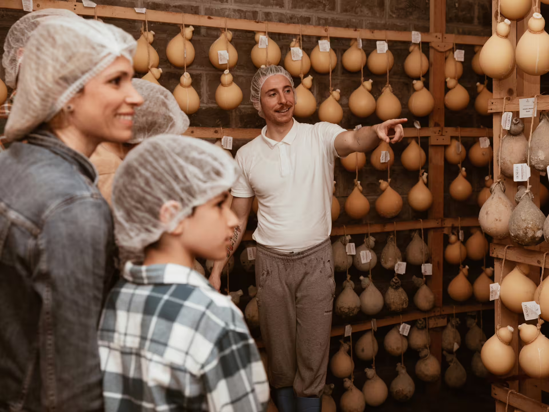 Tour group exploring cheese aging room with a guide in traditional Isernia countryside factory.
