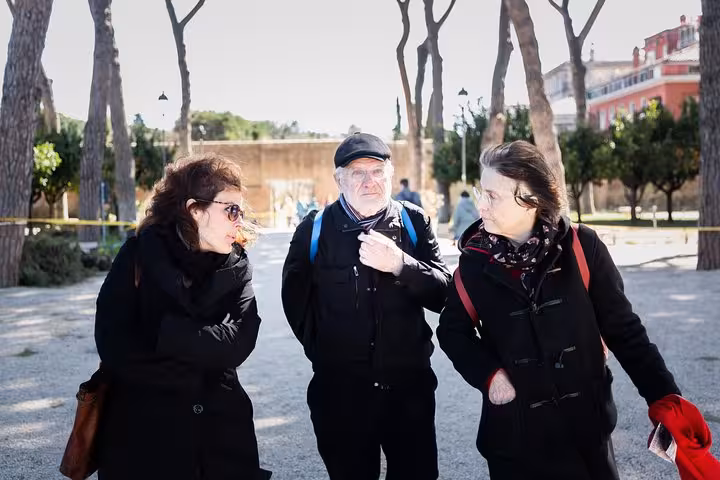 Group of tourists warmly dressed, exploring the tree-lined paths of Rome's Appian Way.