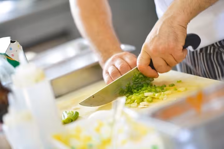 Chef skillfully chopping fresh green onions for an Italian cooking class with unlimited wine experience.