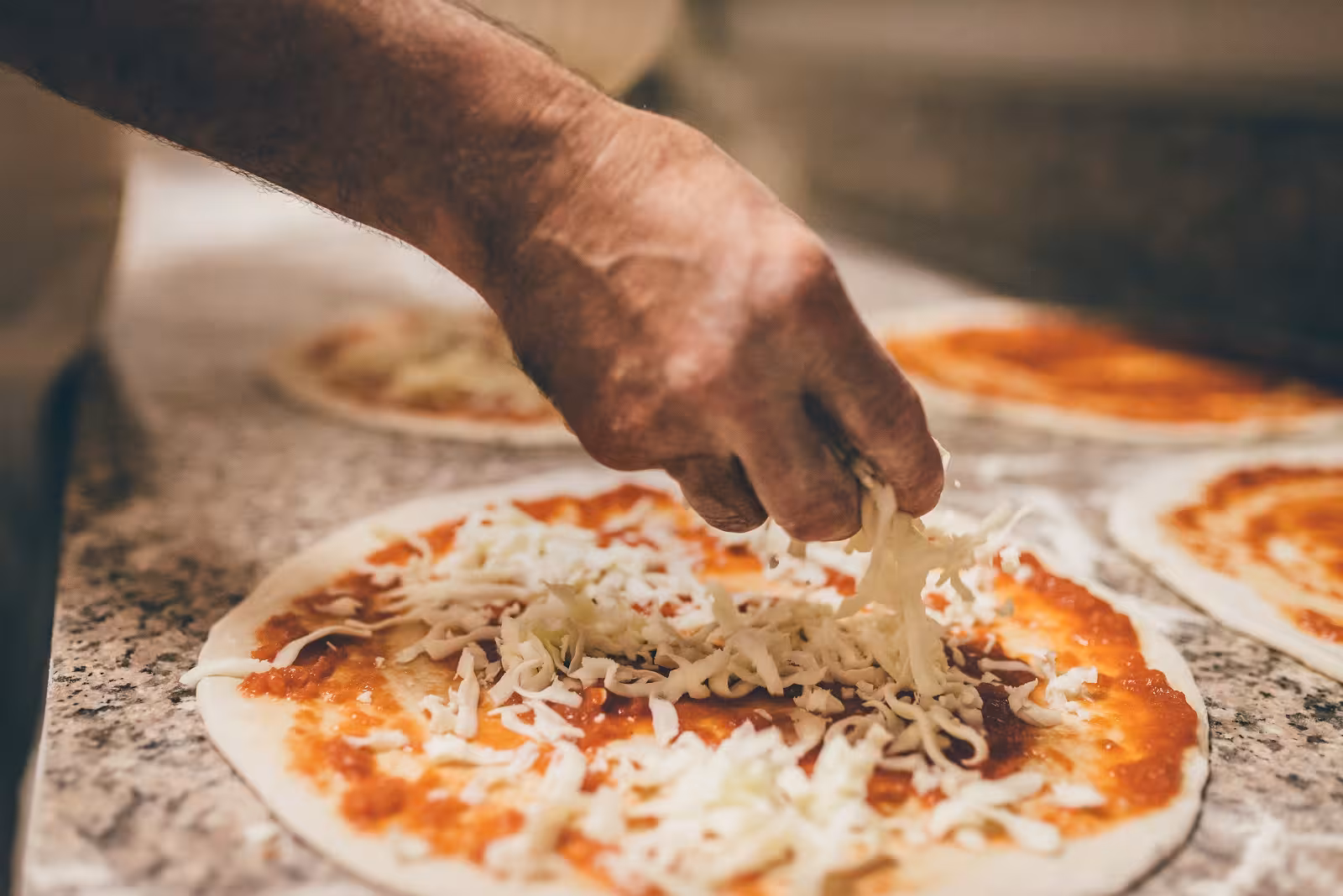 Chef sprinkles fresh mozzarella on pizza at Florence's Italian Way workshop, highlighting authentic culinary skills.