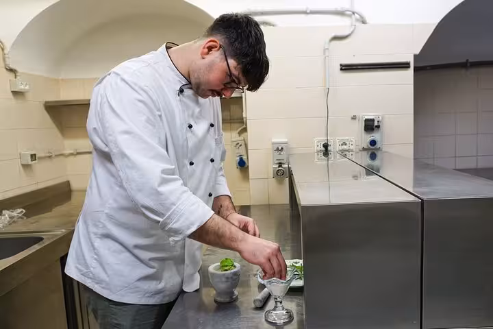 Chef prepares fresh pesto sauce in a modern kitchen during a pasta cooking class in Rome city center.