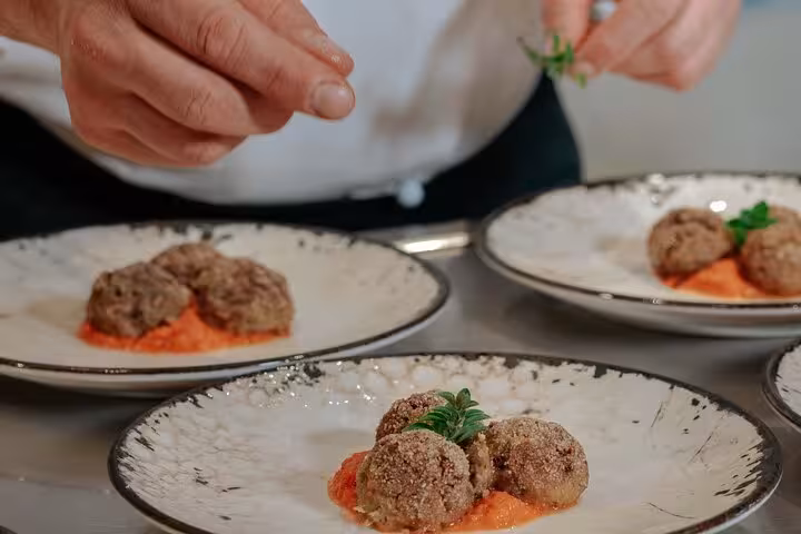 Chef garnishing Italian meatballs in a Tuscan cooking class at MaMa Florence, showcasing authentic culinary techniques.