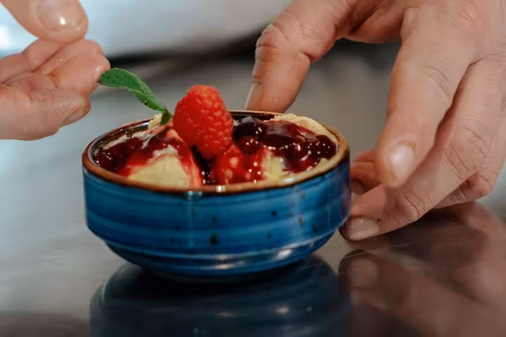Close-up of a chef garnishing raspberry gelato with mint in a Florence cooking class.