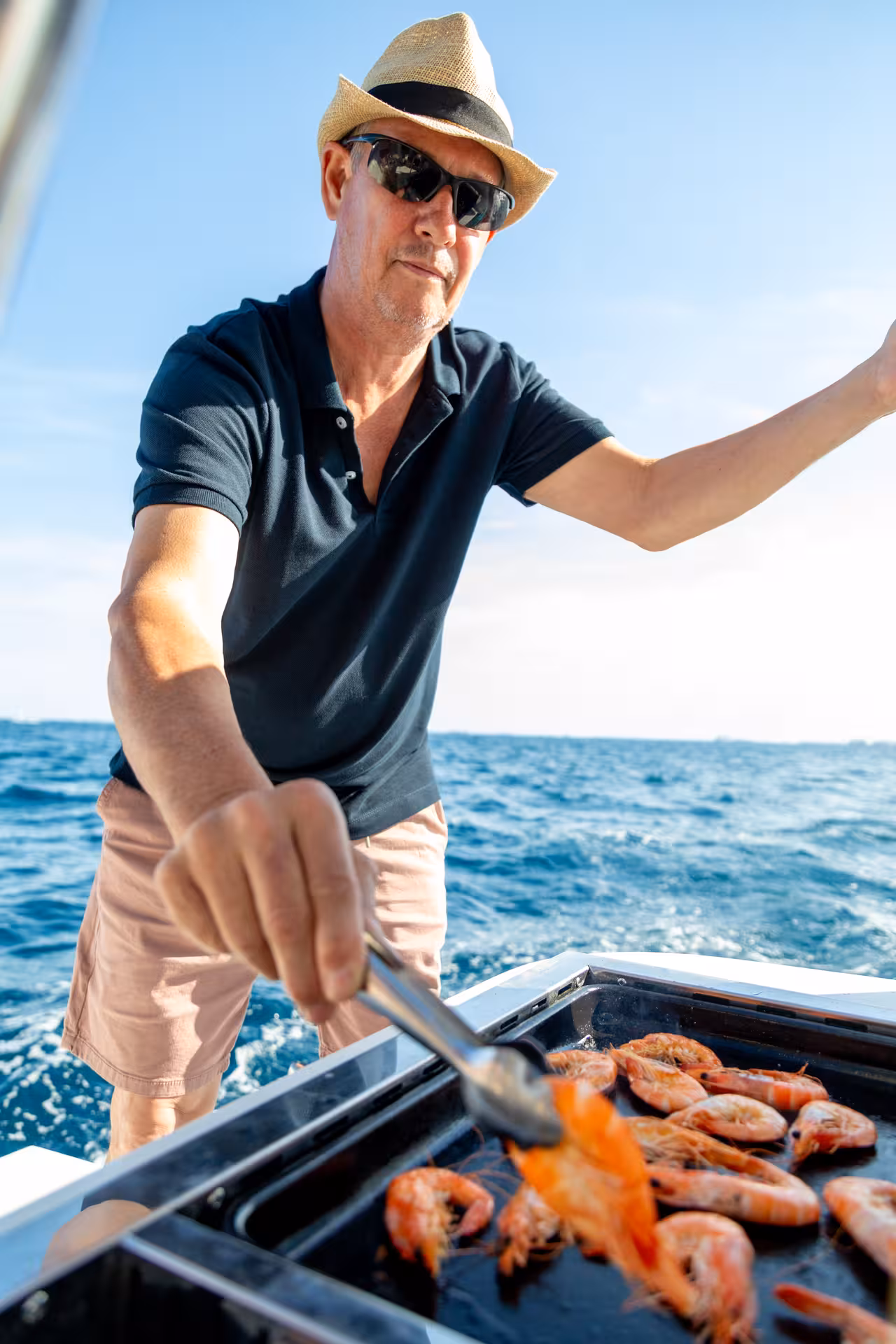 Chef grilling fresh prawns on a boat, hands-on seafood paella masterclass with Mediterranean sea views