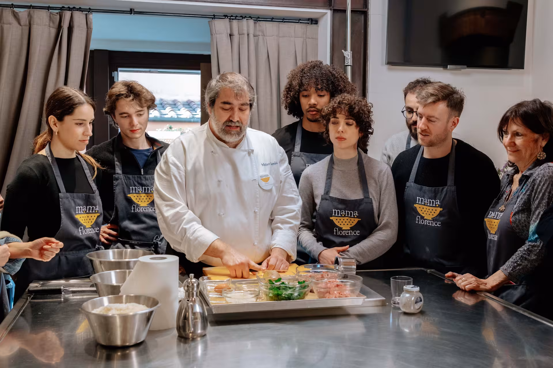 Chef demonstrating pasta-making techniques to engaged students in a Florence cooking class experience.