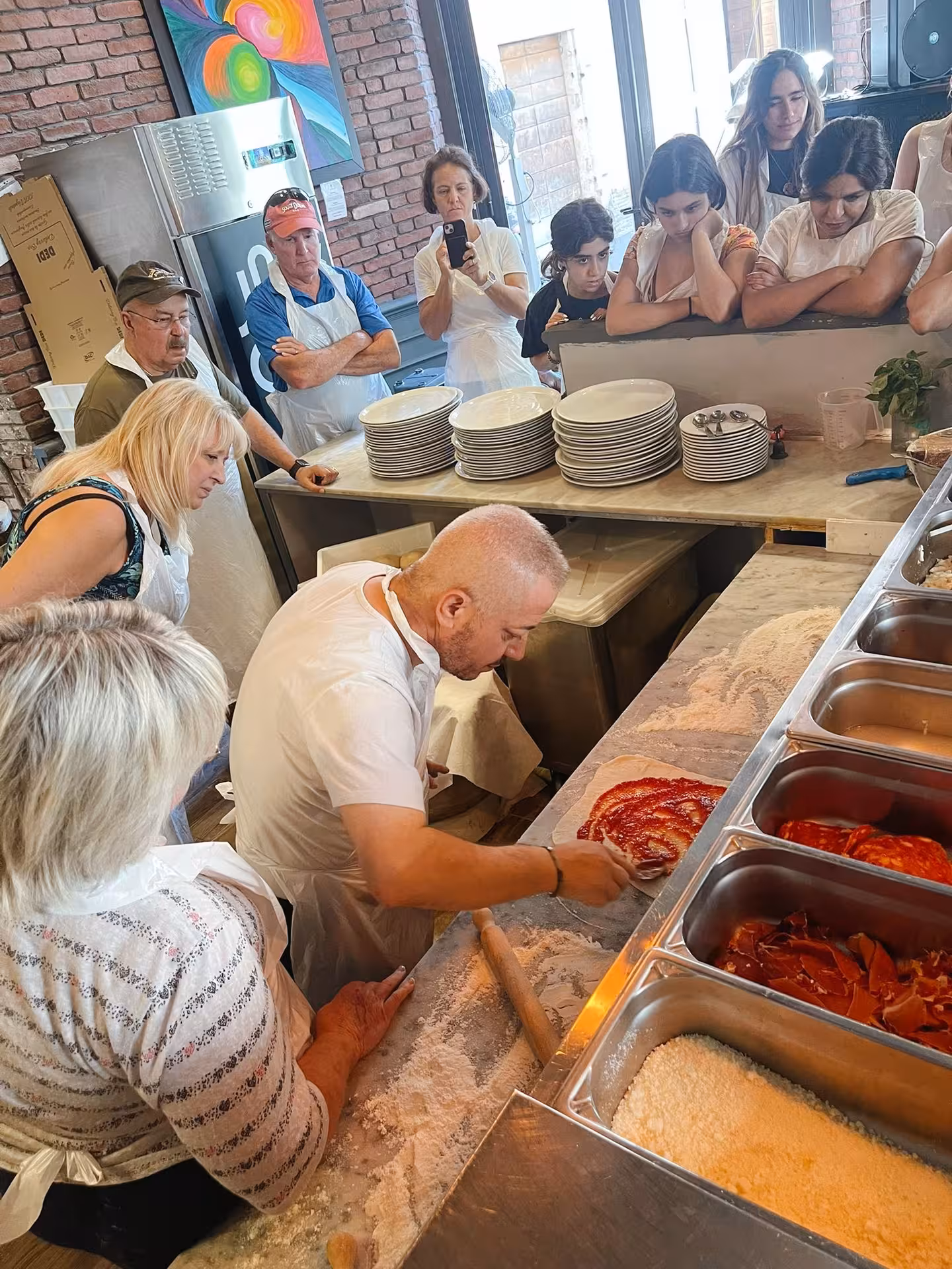 Chef demonstrating pizza sauce application to an attentive group at Jazz Cafe's cooking class in Rome.