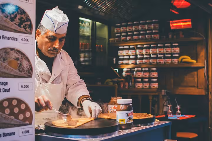 Chef preparing fresh crepes at a traditional Parisian stall, highlighting Le Marais food tour delights.