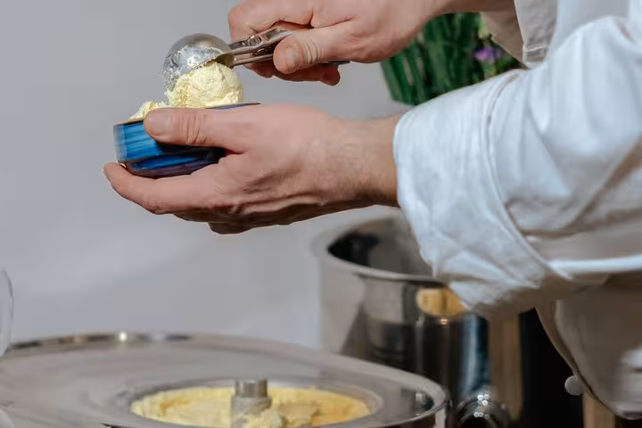 Chef scooping fresh vanilla gelato into a blue bowl during a Florence gelato making class.