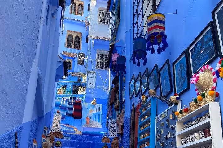 Colorful narrow alley in Chefchaouen adorned with local crafts and art, showcasing the city's iconic blue walls.