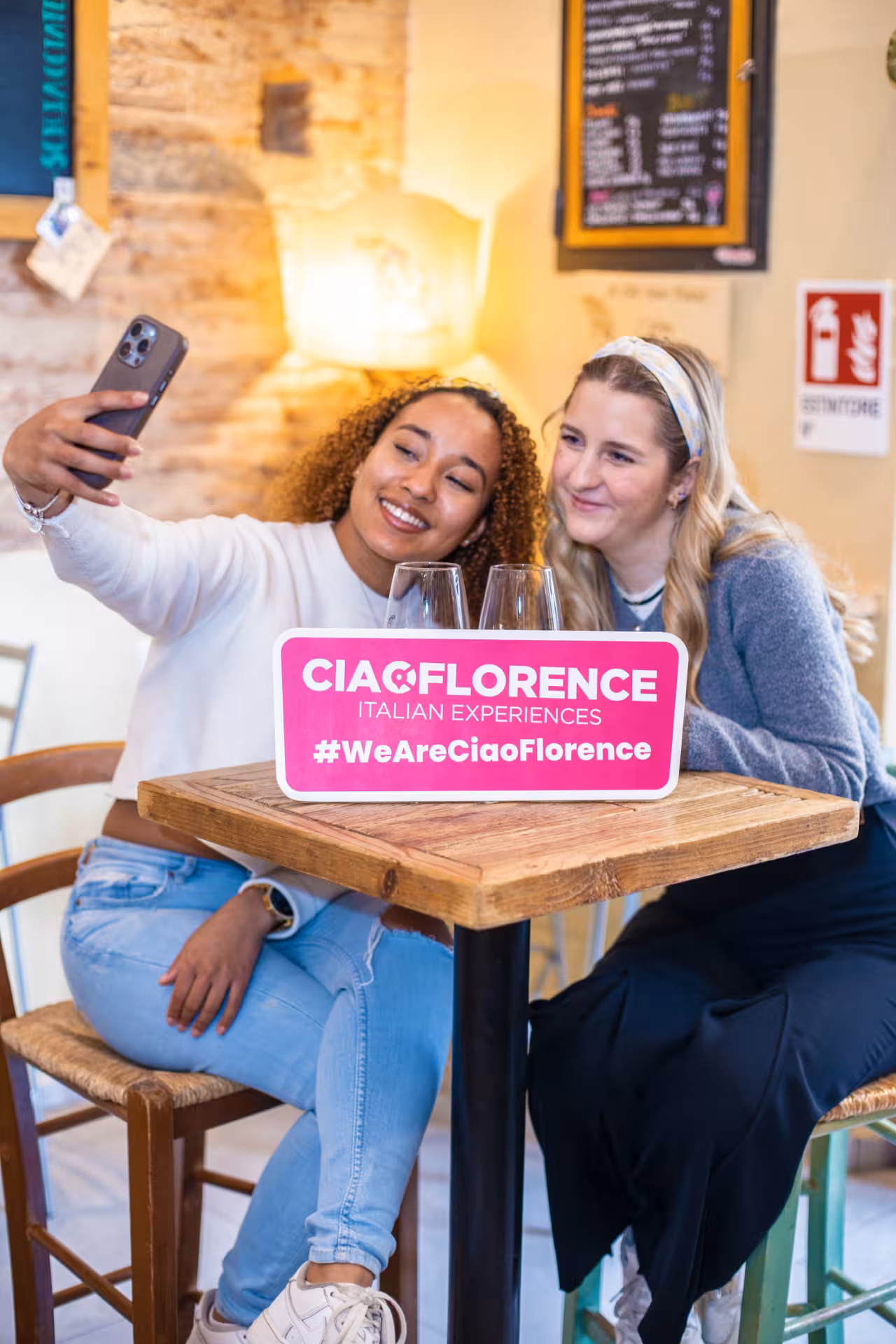 Two women taking a selfie at a cozy café during the Chef’s insights food tour in Sant’Ambrogio, Florence.