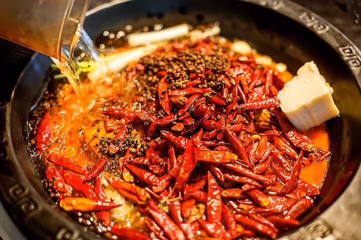 Spicy Sichuan hot pot broth with red chilies and spices, a must-try during Chengdu's culinary city tour.