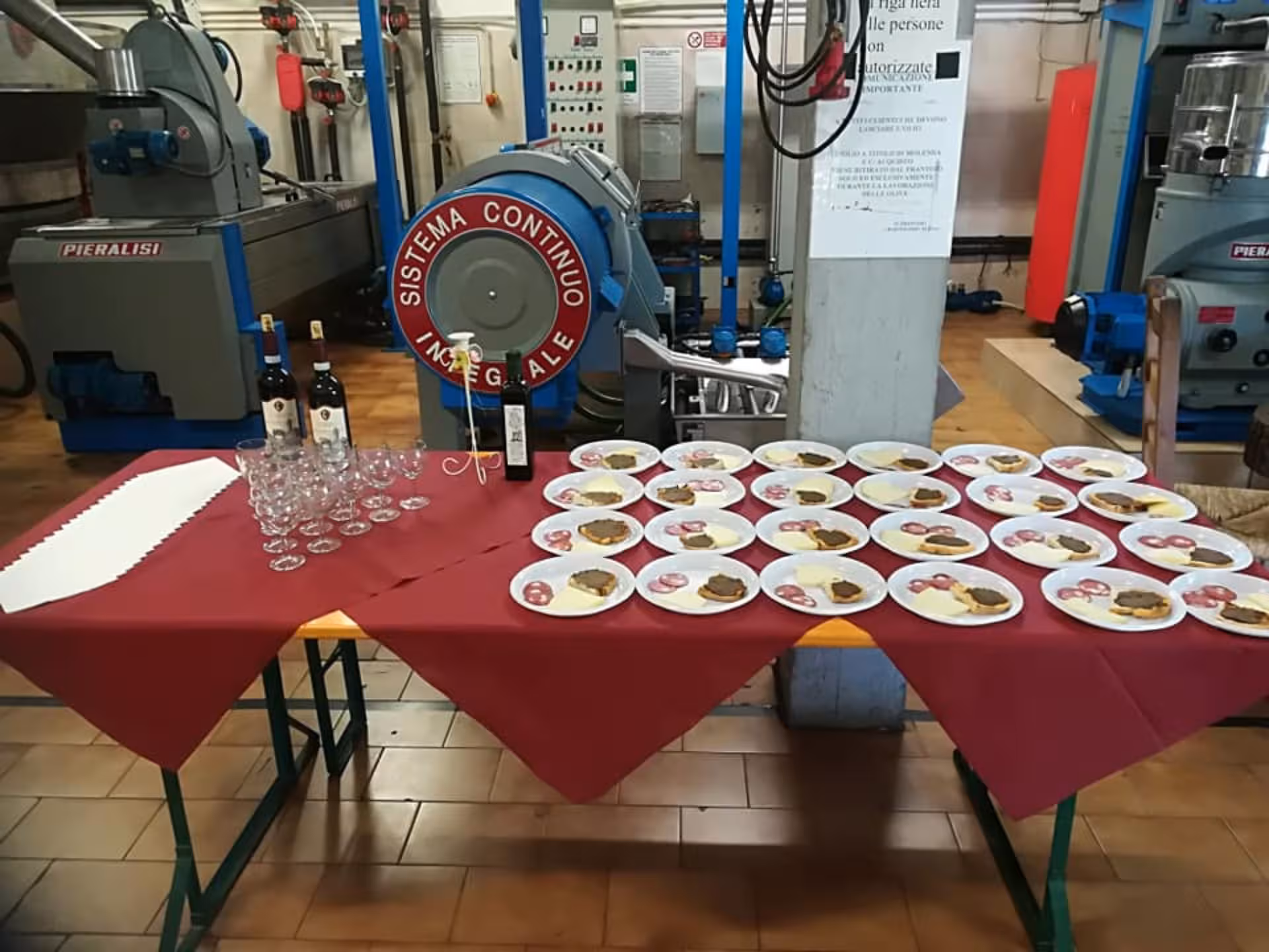 Table set with wine glasses and plates of local delicacies at Chianciano olive mill tour.