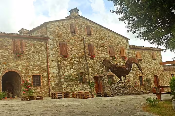 Rustic Tuscan farmhouse winery with stone walls and iconic Chianti Classico Black Rooster sculpture in courtyard