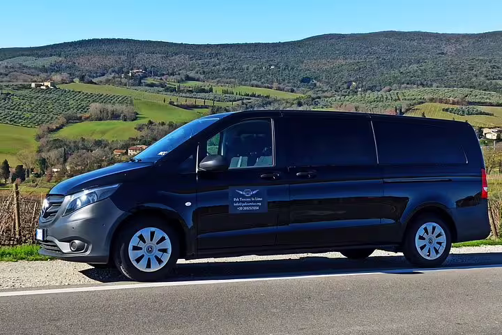 Luxury black minivan for Chianti Classico Black Rooster and Super Tuscan wine tour driving through scenic Tuscan vineyards
