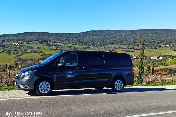 Comfortable black tour van parked along scenic Chianti vineyards and rolling Tuscan hills on a guided countryside ramble