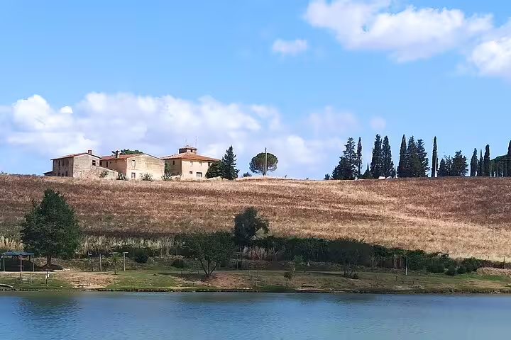 Traditional farmhouse overlooking rolling Chianti hills and vineyard lake on a Tuscany countryside walking and cooking tour