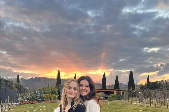Two people smiling in a picturesque Chianti vineyard at sunset, perfect setting for a private tour and wine tasting.