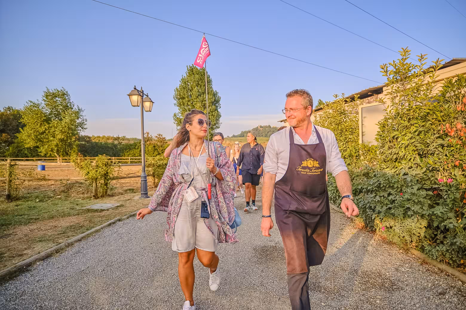 Tour guide and guest walk through Chianti vineyard, enjoying the scenic beauty and rich wine culture.