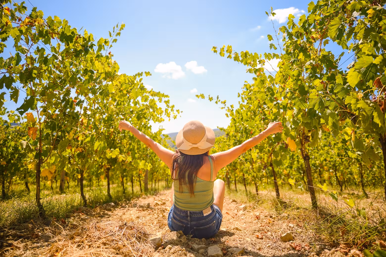 Traveler enjoying the tranquility of a Chianti vineyard, arms raised, embracing the sunny day.
