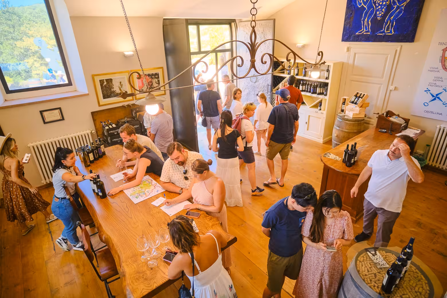 Visitors enjoying wine tasting and engaging in conversations inside a Chianti vineyard tasting room, Tuscany.