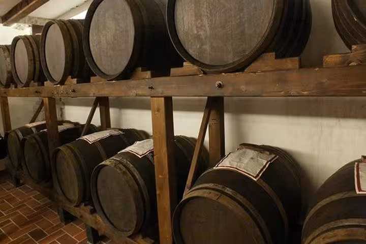 Fila di botti in legno in cantina Chianti, visita e degustazione a Castellina e Greve da Firenze