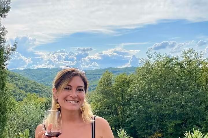 Woman enjoying a glass of wine with a stunning view of Chianti's rolling hills, ideal for a wine tasting experience.