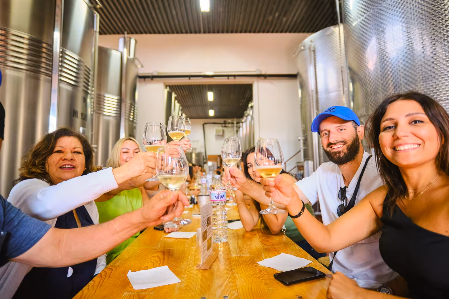 Group enjoying a joyful wine tasting experience in a Chianti winery, surrounded by steel vats.